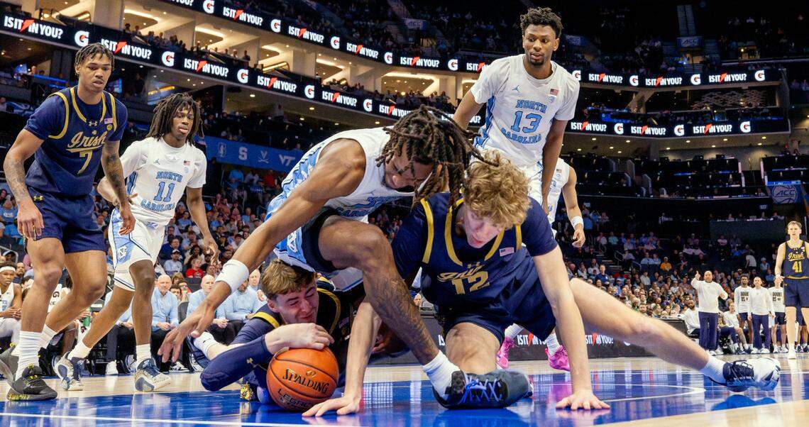 Notre Dame’s J.R. Konieczny (20) dives under North Carolina forward Jalen Washington (13) as he and teammate Garrett Sundra (12) go after a loose ball in the second half on Wednesday, March 12, 2025 during the second round of the ACC Tournament at Spectrum Center in Charlotte, N.C.