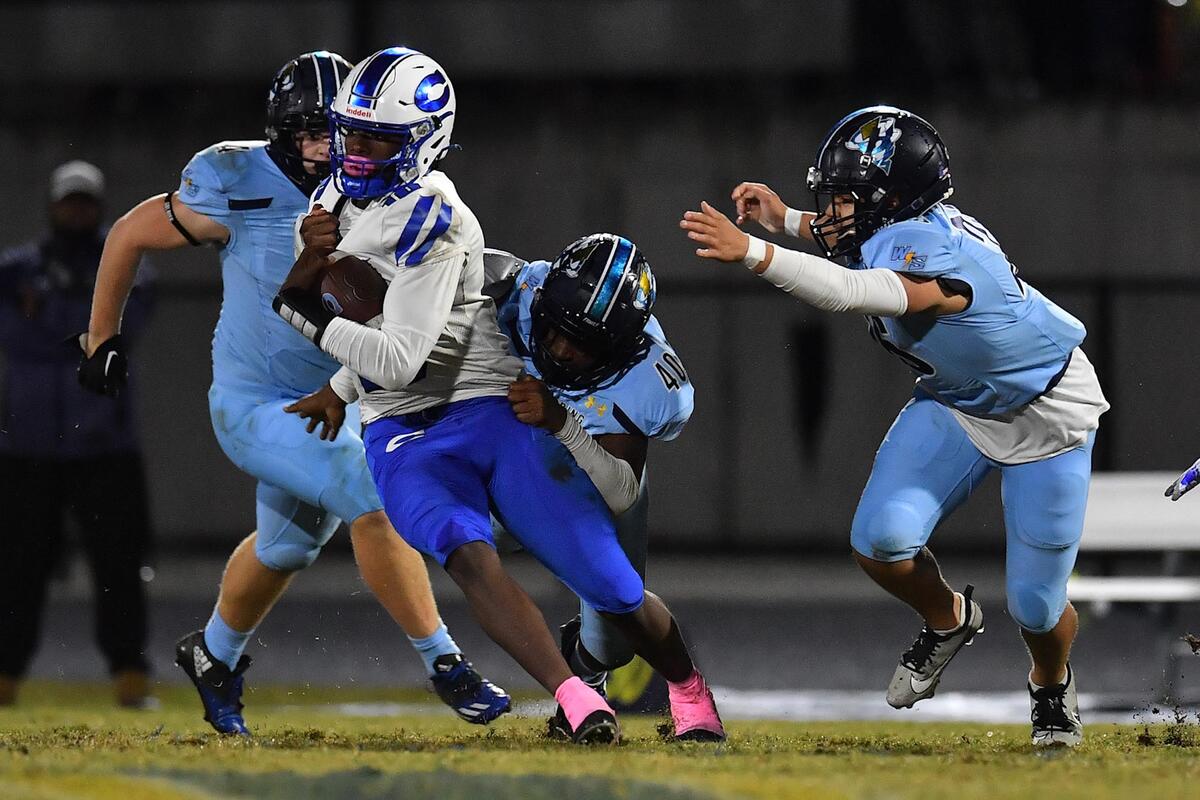 Clayton quarterback Johnathan Montague (10) is grappled by Willow Spring’s Angus Ledgester (40) and pursued by the defense during the first half. The Clayton Comets and the Willow Spring Storm met in a conference football game in Fuquay-Varina, N.C. on October 20, 2023.