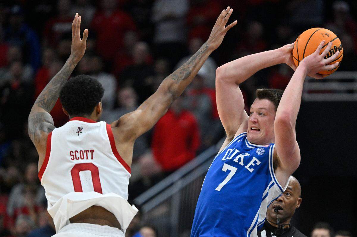 Duke Blue Devils guard Kon Knueppel (7) looks to pass under the pressure of Louisville Cardinals forward James Scott (0) during the first half at KFC Yum! Center on Sunday, Dec. 8, 2024.