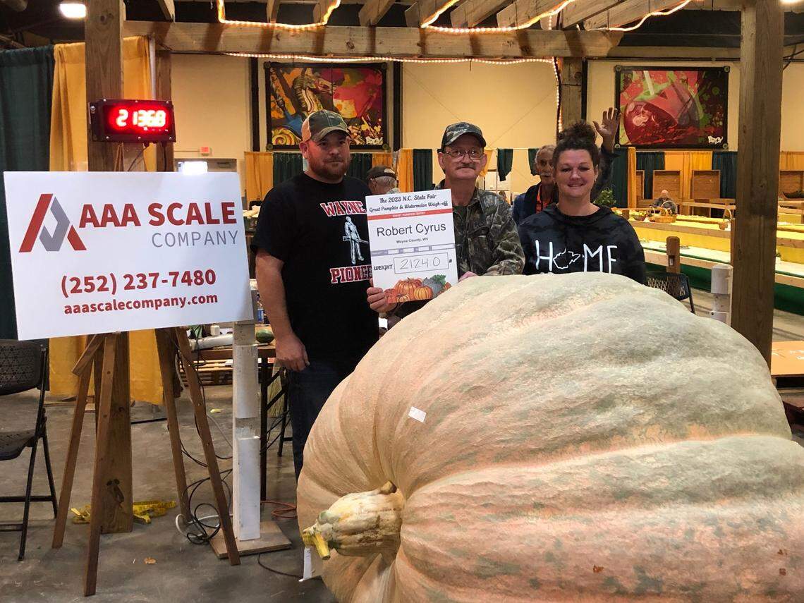 Robert Cyrus, center, with “Ruby,” his 2,124-pound pumpkin that took the top prize in this year’s giant produce competition at the N.C. State Fair on Tuesday. Cyrus lives in West Virginia and has been competing for eight years.