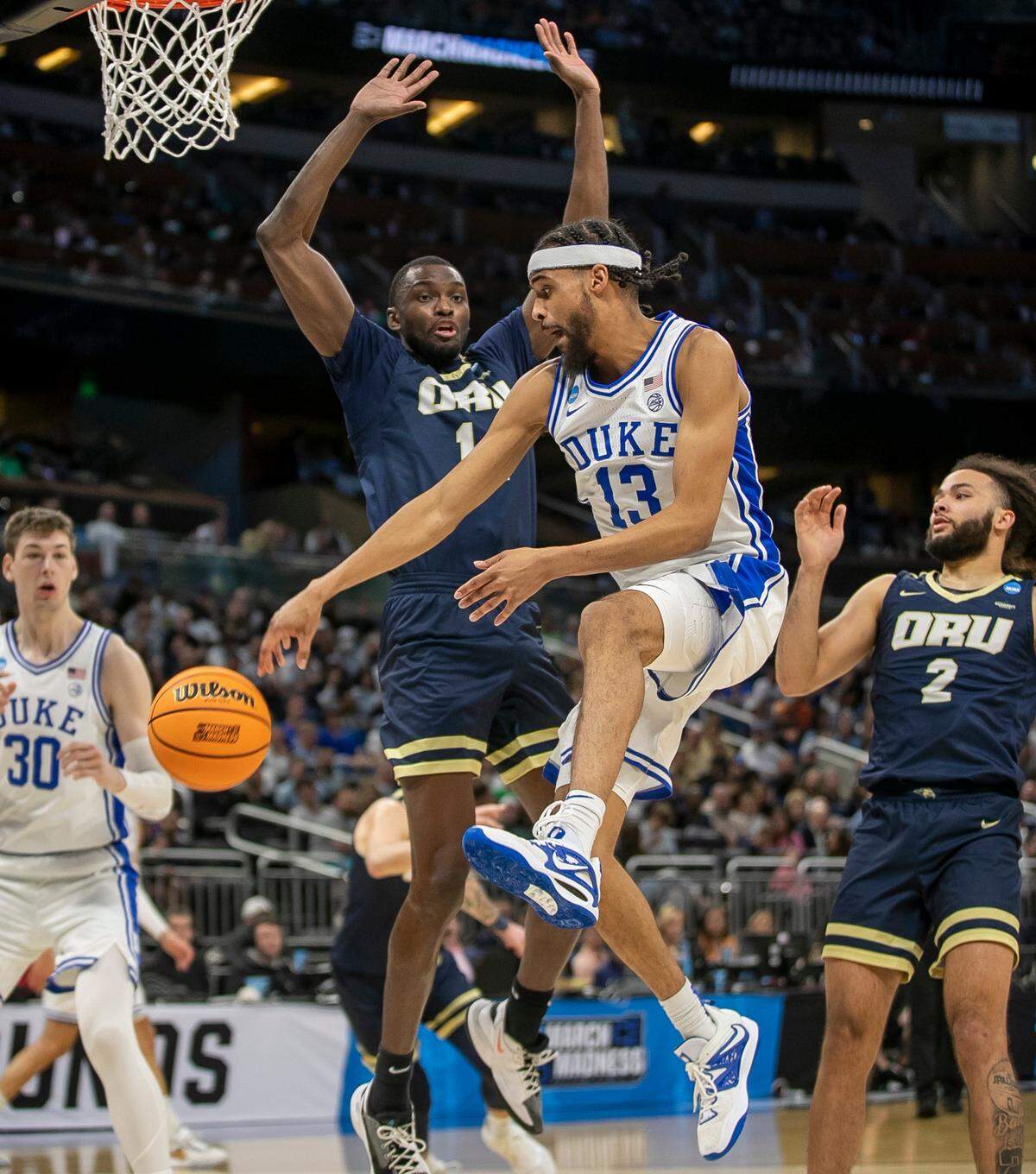 Duke’s Jacob Grandison (13) passes around Oral Roberts’ DeShang Weaver (14) to Kyle Filipowski (30) in the second half during the first round of the NCAA Tournament on Thursday, March 16, 2023 at the Amway Center in Orlando, Fla.