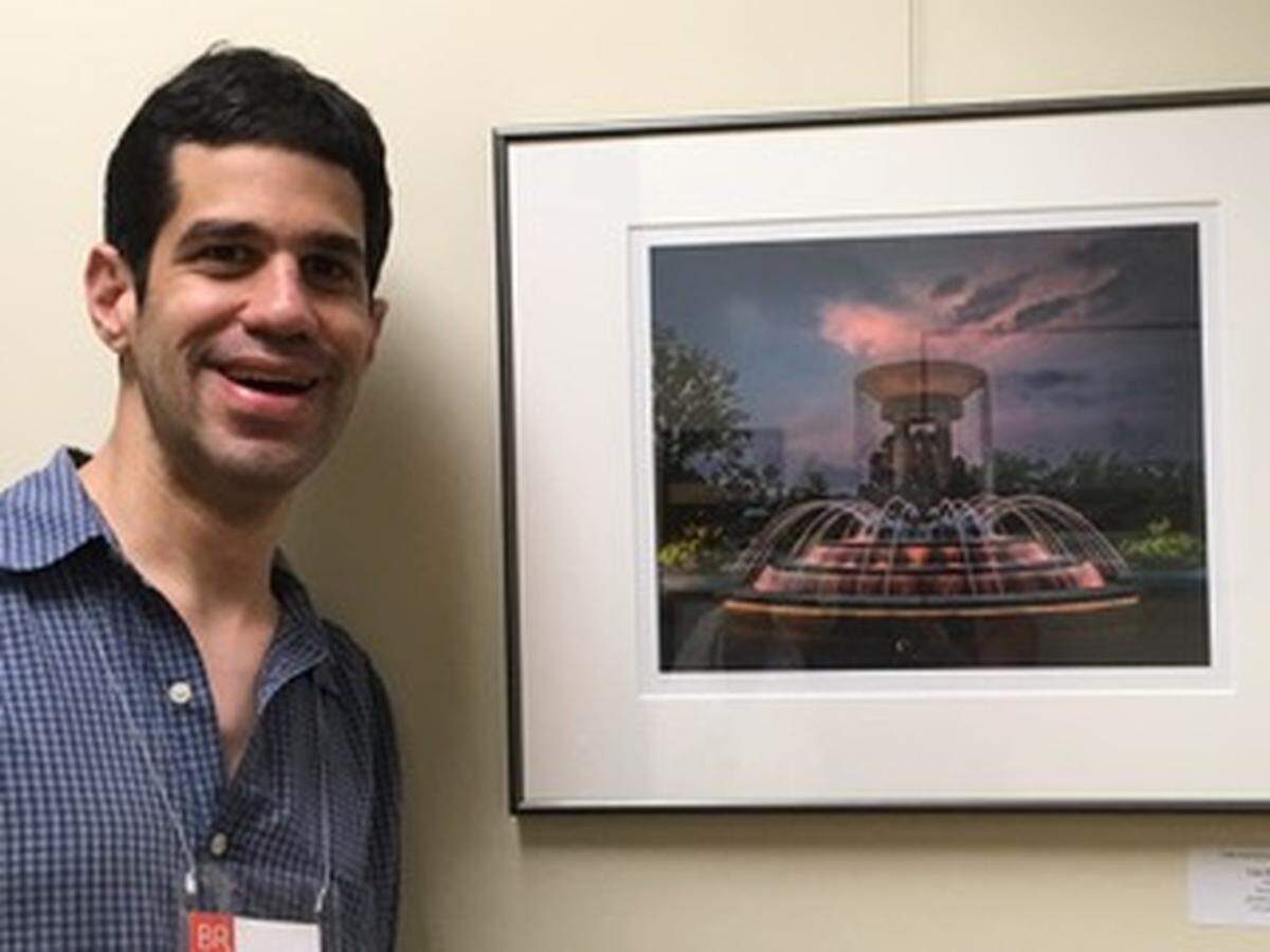 Brian Raia pictured at a photo reception at the Cary Arts Center in May, for his picture of Cary’s downtown park fountain. Brian was diagnosed with Autism at a young age and has been waiting almost a decade for the NC Innovations Waiver to receive services. 