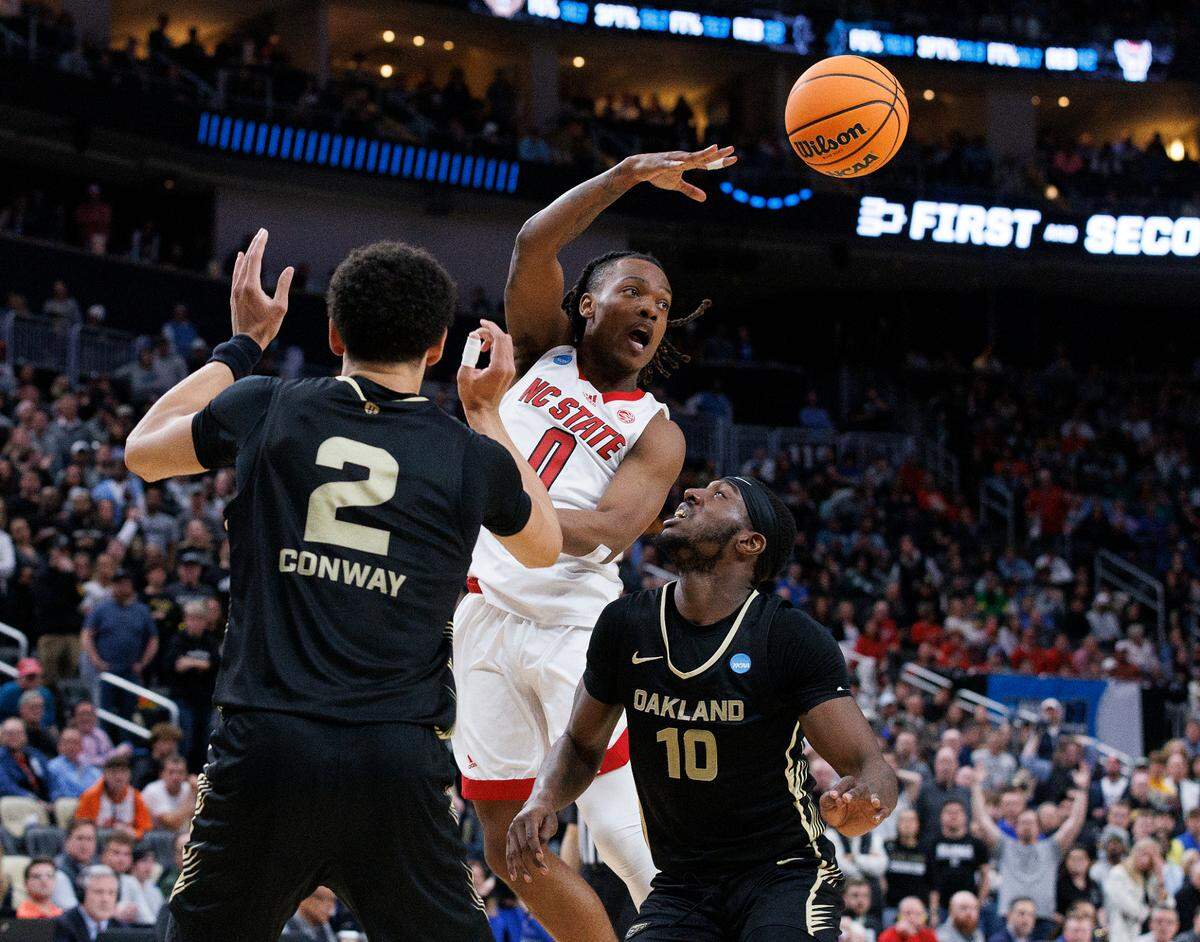 N.C. State’s DJ Horne looks to pass around Oakland’s Chris Conway and DQ Cole during overtime of the Wolfpack’s 79-73 win in the second round of the NCAA Tournament on Saturday, March 23, 2024, at PPG Paints Arena in Pittsburgh, Pa.