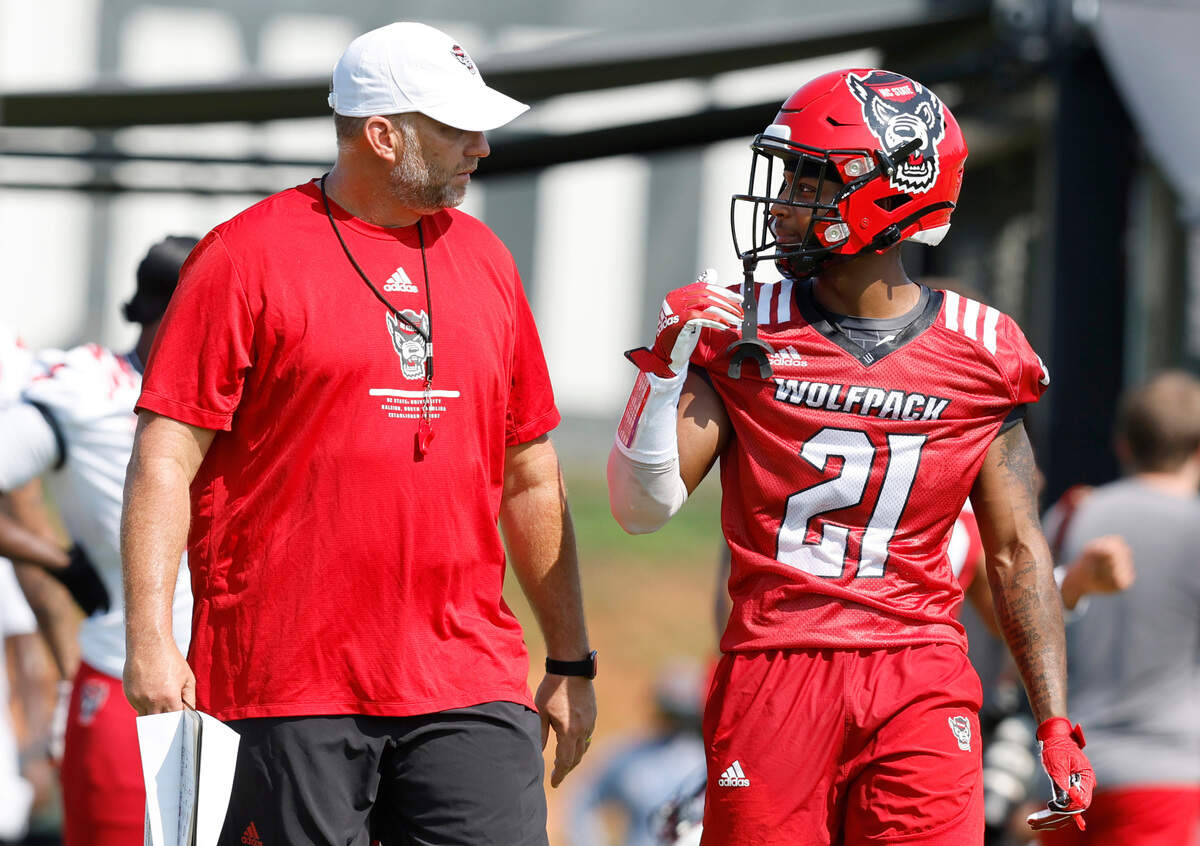 N.C. State head coach Dave Doeren talks with cornerback Nate Evans (21) during the Wolfpack’s football’s first practice of fall camp in Raleigh, N.C., Wednesday, August 3, 2022.