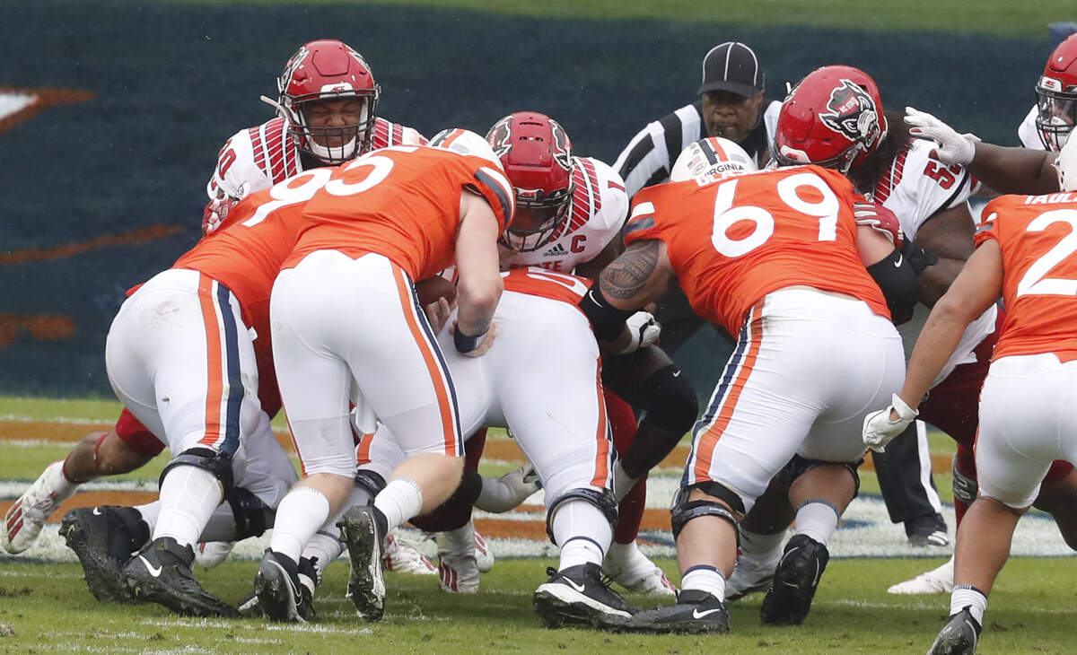 On fourth and one at the goal line, N.C. State’s Savion Jackson (90), Isaiah Moore (1) and Joshua Harris (55) help stop Virginia quarterback Brennan Armstrong (5) for no gain during the first half of N.C. State’s game against Virginia at Scott Stadium in Charlottesville, Va., Saturday, Oct. 10, 2020.