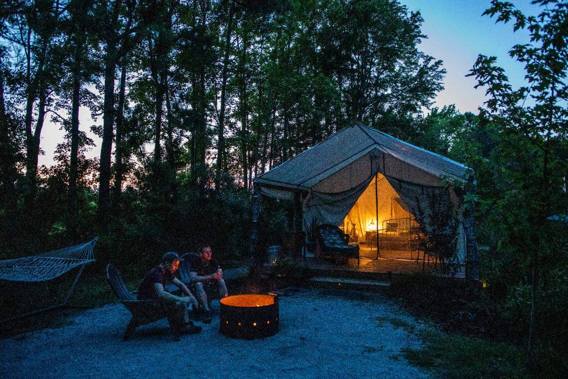 German tourists Timo Schneider, left, and Niklas Erfel sit at a camp fire at one of Holden Beach RV Campground’s “glamping” tents.