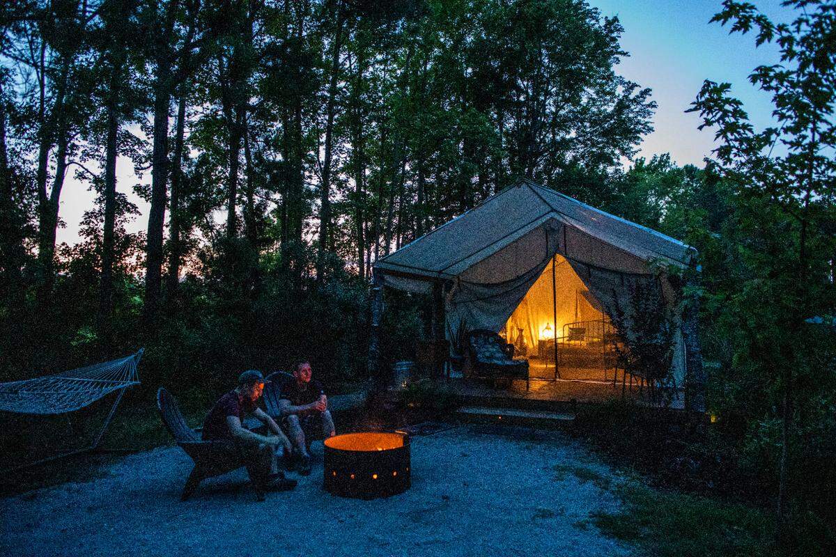 German tourists Timo Schneider, left, and Niklas Erfel sit at a camp fire at one of Holden Beach RV Campground’s “glamping” tents.