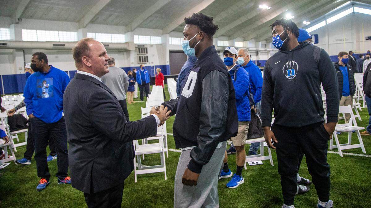 Mike Elko talks with players Caleb Oppan, center, and Peace Addo after being introduced as Duke University’s head football coach during a press conference at Pascal Field House in Durham, Monday, Dec. 13, 2021.