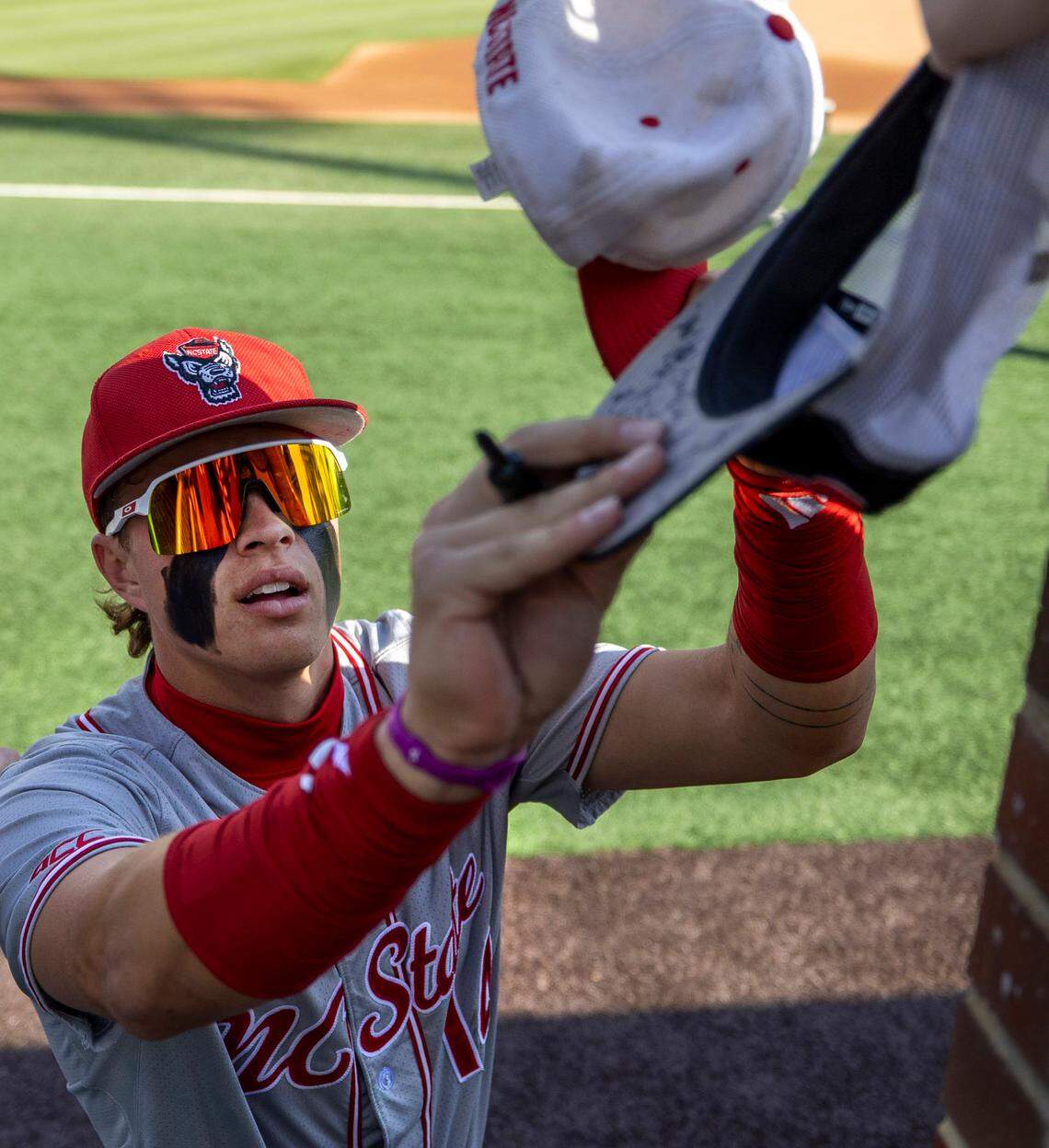 N.C. State outfield Ty Head (14) autographs hats for fans prior to the Wolfpack’s game against the North Carolina Tar Heels on Friday, May 9, 2025 at Boshamer Stadium in Chapel Hill, N.C.