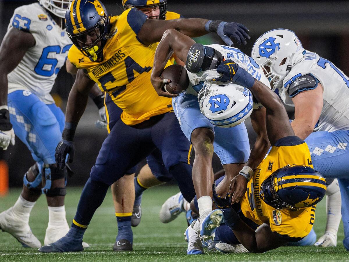 North Carolina quarterback Conner Harrell (15) is sacked for a eight-yard loss in the third quarter by West Virginia’s Tomiwa Durojaiye (3) during the Duke’s Mayo Bowl on Wednesday, December 27, 2023 at Bank of American Stadium in Charlotte, N.C. The Mountaineers held the Tar Heels scoreless in the second half and rolled to a 30-10 victory.