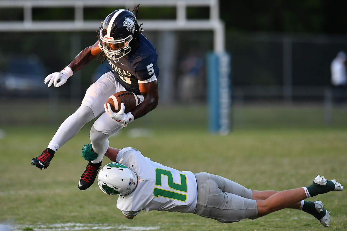 Southeast Raleigh running back Christian Freeman (5) leaps over Cardinal Gibbons defensive back Drake Stone (12) during the first half. The Southeast Raleigh Bulldogs and the Cardinal Gibbons Crusaders met in a non-conference football game in Raleigh, N.C. September 12, 2025