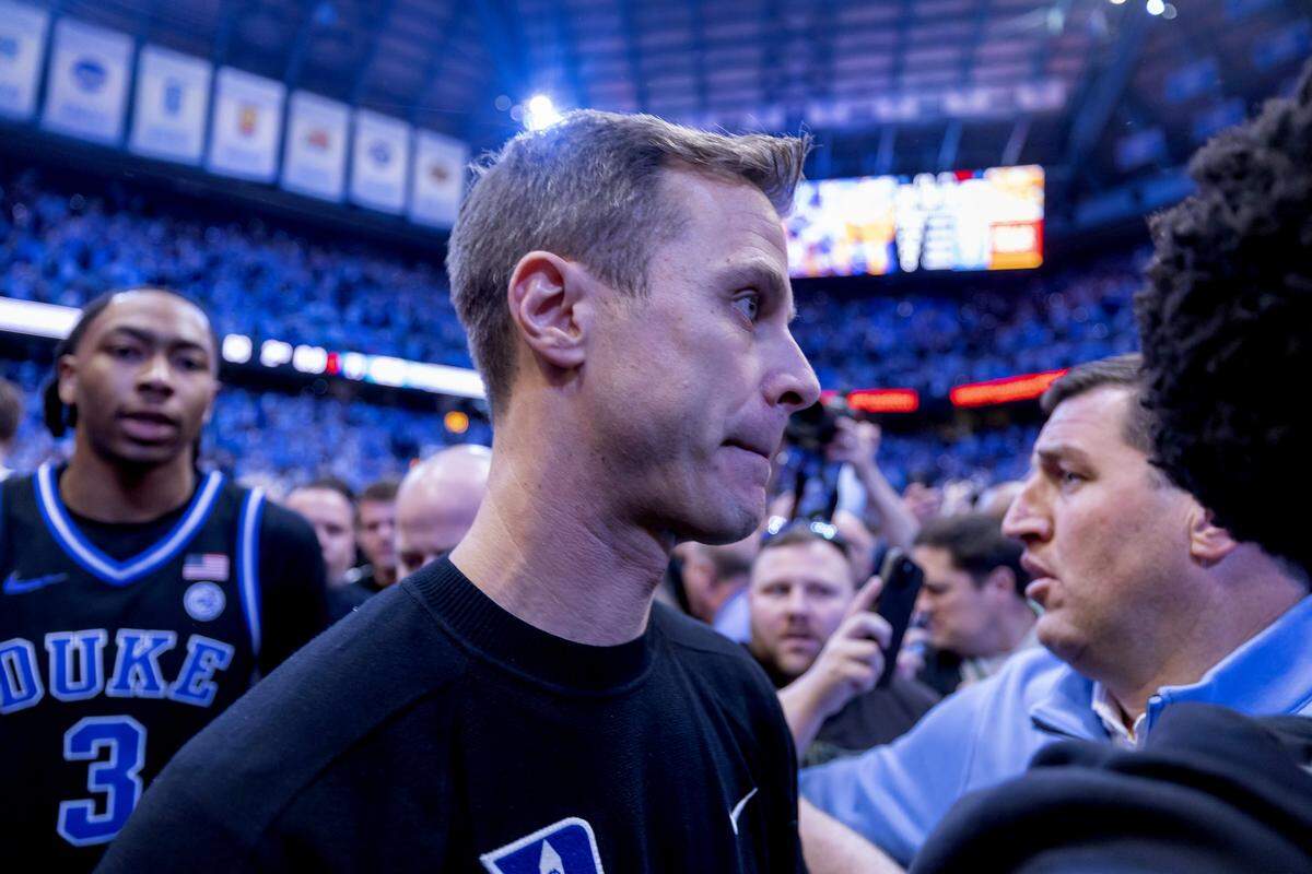 Duke coach Jon Scheyer is surrounded by North Carolina fans who stormed the court following Seth Trimble’s game winning three-point shot with .4 second to play on Saturday, February 7, 2026 at the Smith Center in Chapel Hill, N.C.  Scheyer voiced his disappointment at not being able to get off the court safely at the end of the game.