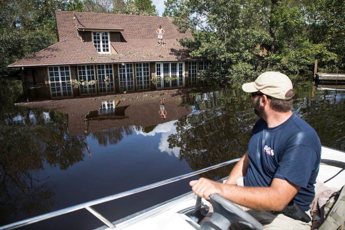 Jason Atoigue speaks with a resident of the River Bend neighborhood, which sits on the Northeast Cape Fear River in Burgaw on Sunday, Sept. 23, 2018. The resident was checking on trees resting on the roof of the flooded home.