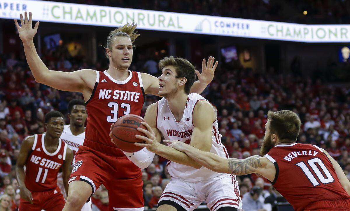 Wisconsin’s Ethan Happ, center, is fouled by North Carolina State’s Braxton Beverly (10) during the second half of an NCAA college basketball game Tuesday, Nov. 27, 2018, in Madison, Wis. At left is North Carolina State’s Wyatt Walker (33).