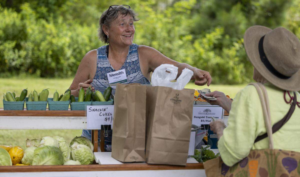 Meredith Leight of Granite Springs Farm sells produce to Carlyle Poteat of Pittsboro during the weekly Farmer’s Market at The Plant on Thursday, July 3, 2025 in Pittsboro, N.C.