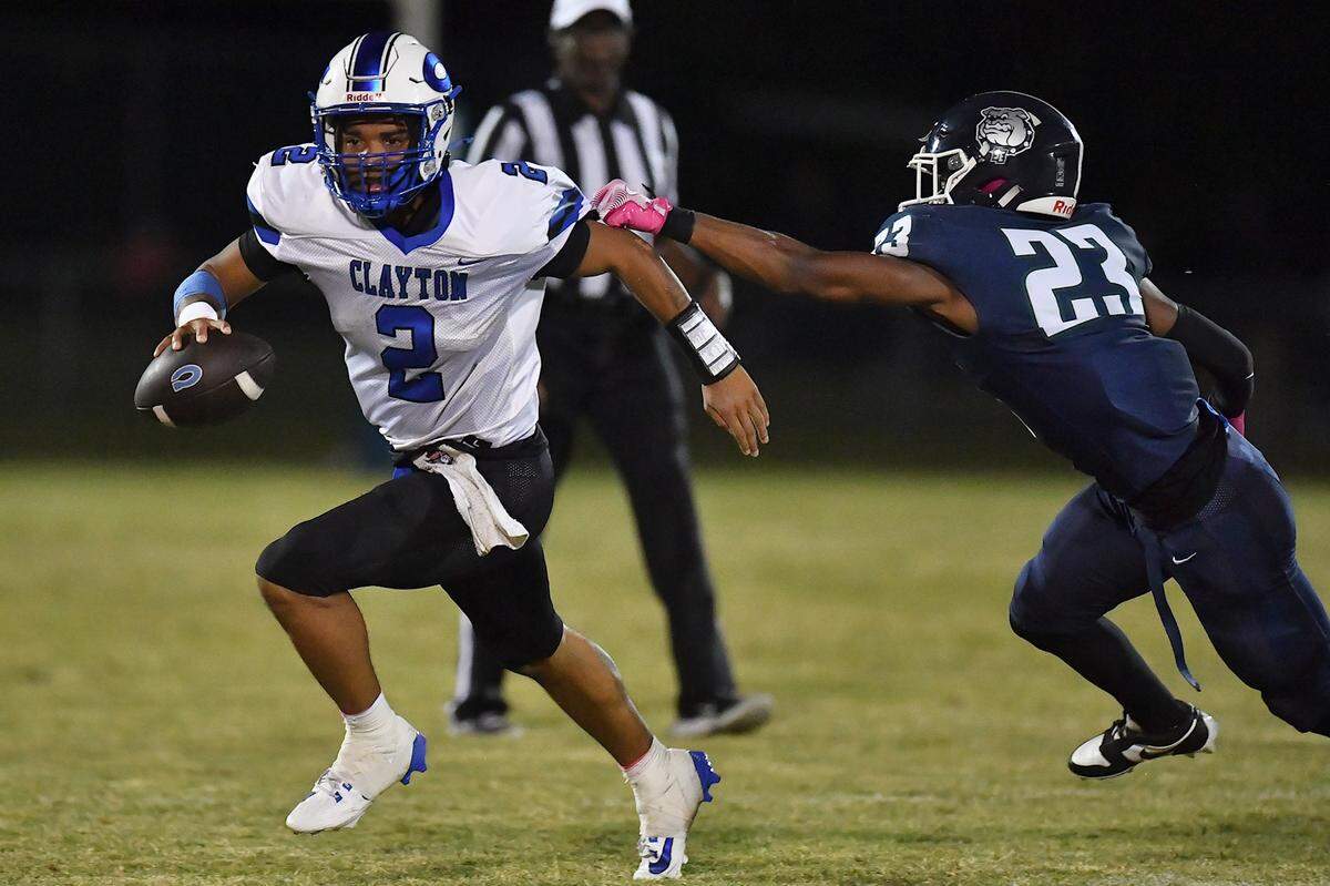 Clayton quarterback Aiden Smalls (2) runs towards the sidelines against Southeast Raleigh linebacker DeAdrian Williams (23) during the first half. The Southeast Raleigh Bulldogs and the Clayton Comets met in a non-conference football game in Raleigh, N.C. October 3, 2025