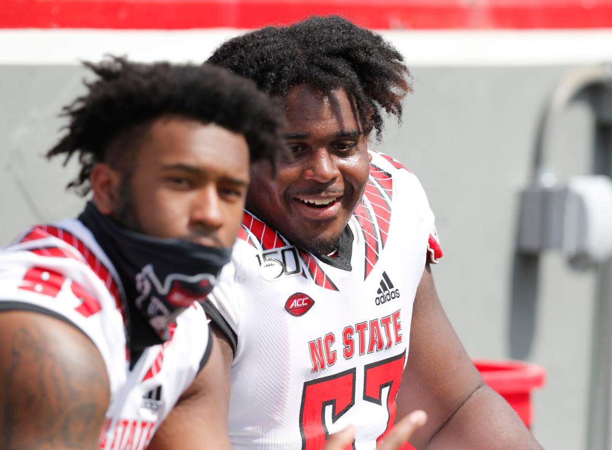 N.C. State’s Lyndon Cooper (57), right, and Claude Larkins take a break during the Wolfpack’s spring game at Carter-Finley Stadium in Raleigh, N.C., Saturday, April 10, 2021.