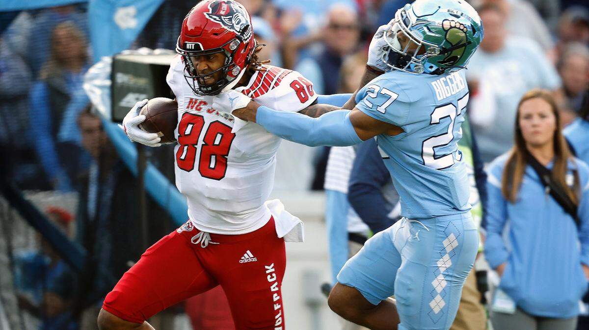 N.C. State wide receiver Devin Carter (88) stiff-arms North Carolina defensive back Giovanni Biggers (27) as he gains yards after a catch during the first half of N.C. State’s game against UNC at Kenan Stadium in Chapel Hill, N.C., Friday, Nov. 25, 2022.