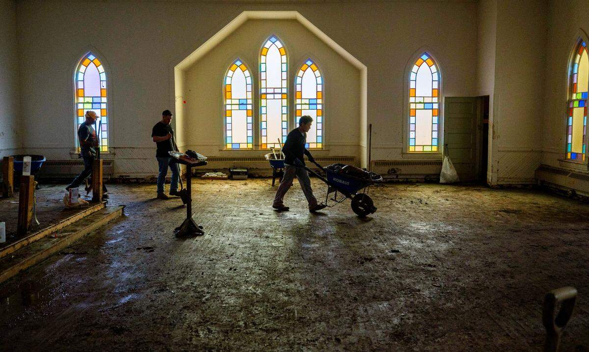Johnny Bolick, a member of IChurch from Hickory, N.C., pushes a wheel barrow of debris from the sanctuary of Old Fort United Methodist Church on Saturday, October 5, 2024 in Old Fort, N.C. More than four feet of water from Mill Creek flooded the building during Hurricane Helene.