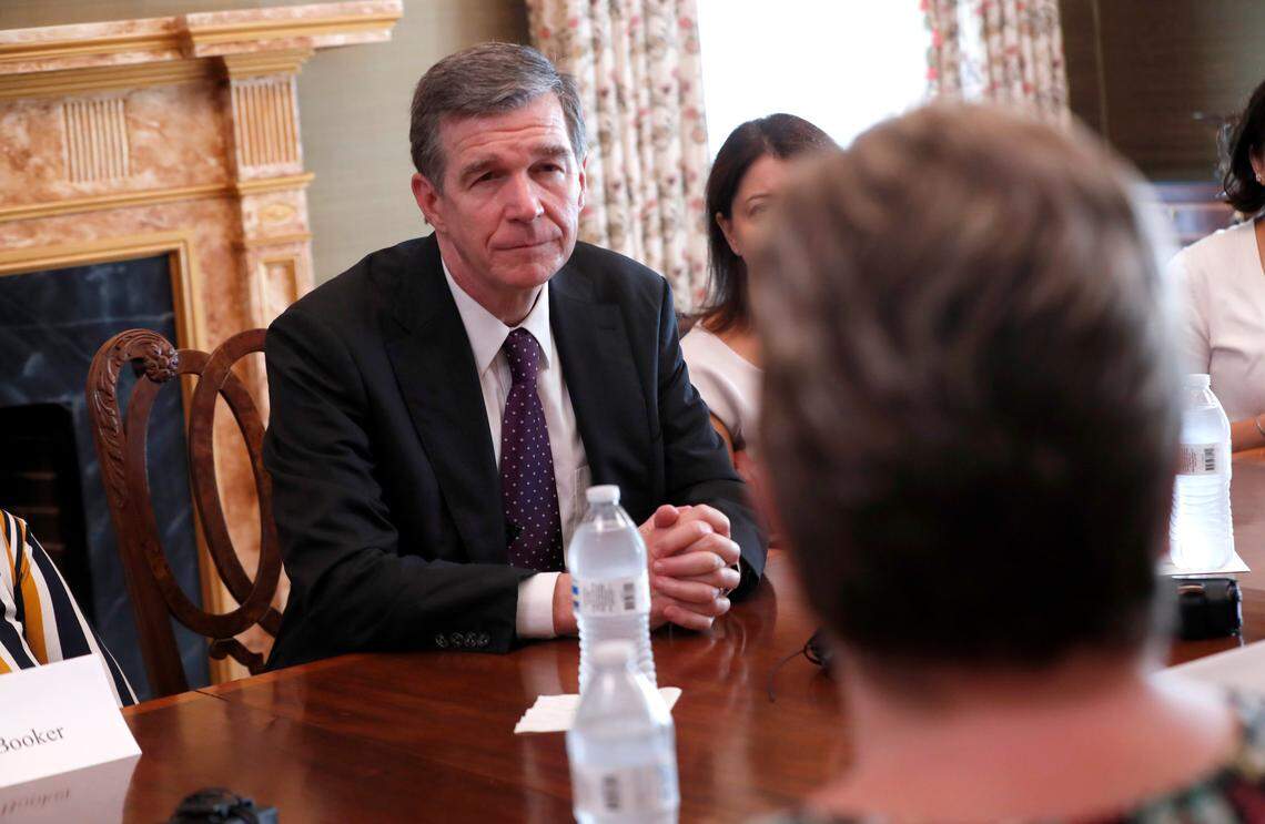 Gov. Roy Cooper listens to Robin Jordan as he talks with North Carolina residents who do not have health insurance during a roundtable at the Andrews-London House in Raleigh, N.C., Wednesday, July 17, 2019.
