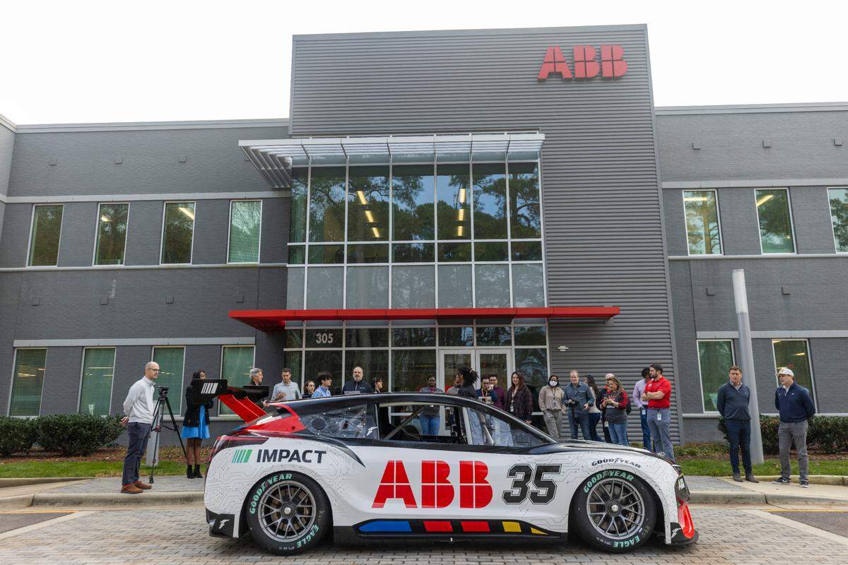 A crowd gathers around a prototype electric race car at ABB in Cary on Dec. 18, 2024. The prototype was developed at NASCAR’s Research and Development Center in Concord by a team that included Chevrolet, Ford and Toyota.