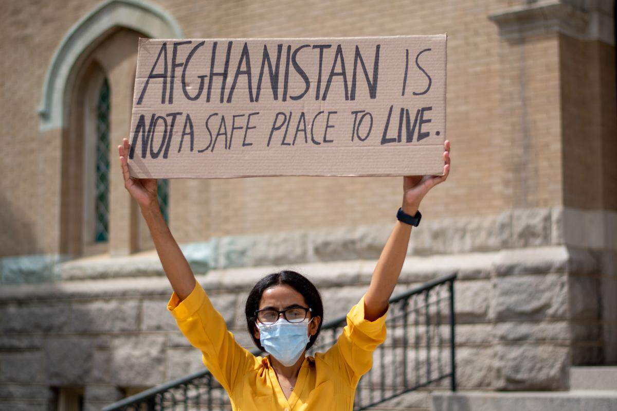 Zahra Mohammadi, an Afghan refugee resettled in Durham, standing with a handwritten sign during a small demonstration with her sisters in front of the Duke Memorial United Methodist Church in downtown Durham on Friday, August 6, 2021.