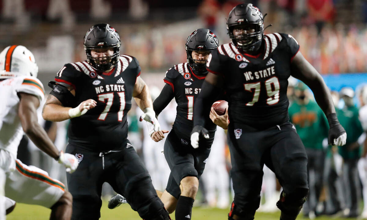 N.C. State quarterback Bailey Hockman (16) runs behind blockers Joe Sculthorpe (71) and Ikem Ekwonu (79) for a 31-yard touchdown reception during the first half of N.C. State’s game against Miami at Carter-Finley Stadium in Raleigh, N.C., Friday, Nov. 6, 2020.