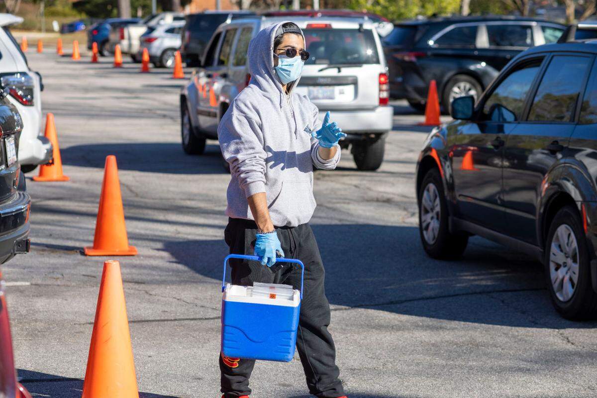 Staff collect COVID-19 test kits, and direct the public in and out of the parking lot on Kidd Road at a Wake County COVID-19 testing site on Thursday, December 23, 2021 in Raleigh, N.C.