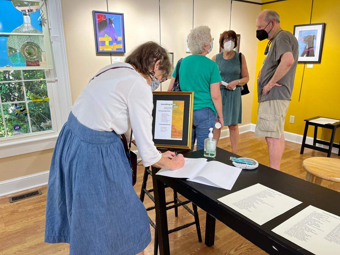 Attendees mingle at the Something to Say art show at Margaret Lane Gallery in Hillsborough on Saturday, June 30, 2022. The message book, positioned at the center of the gallery room, was filled with messages of hope and perseverance by the end of the event.