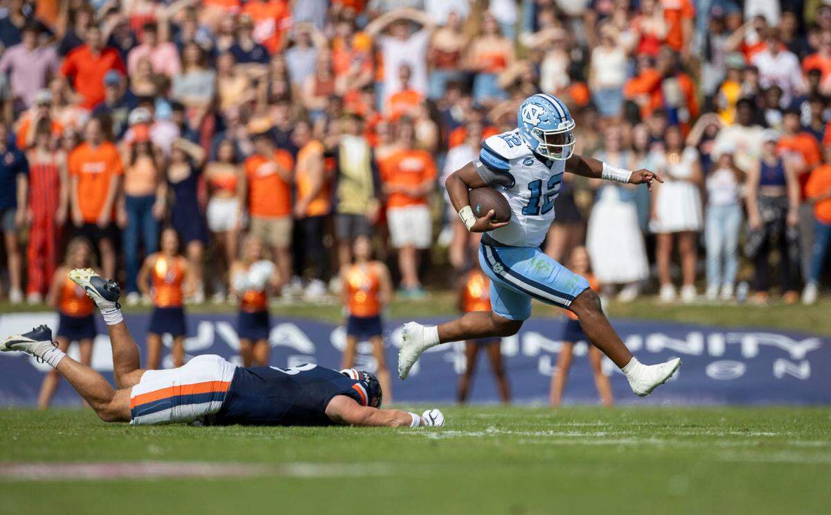 North Carolina quarterback Jacolby Criswell (12) rushes for 19 yards in the first quarter ahead of Virginia linebacker Trey McDonald (8) on Saturday, October 26, 2024 at Scott Stadium in Charlottesville, Va.