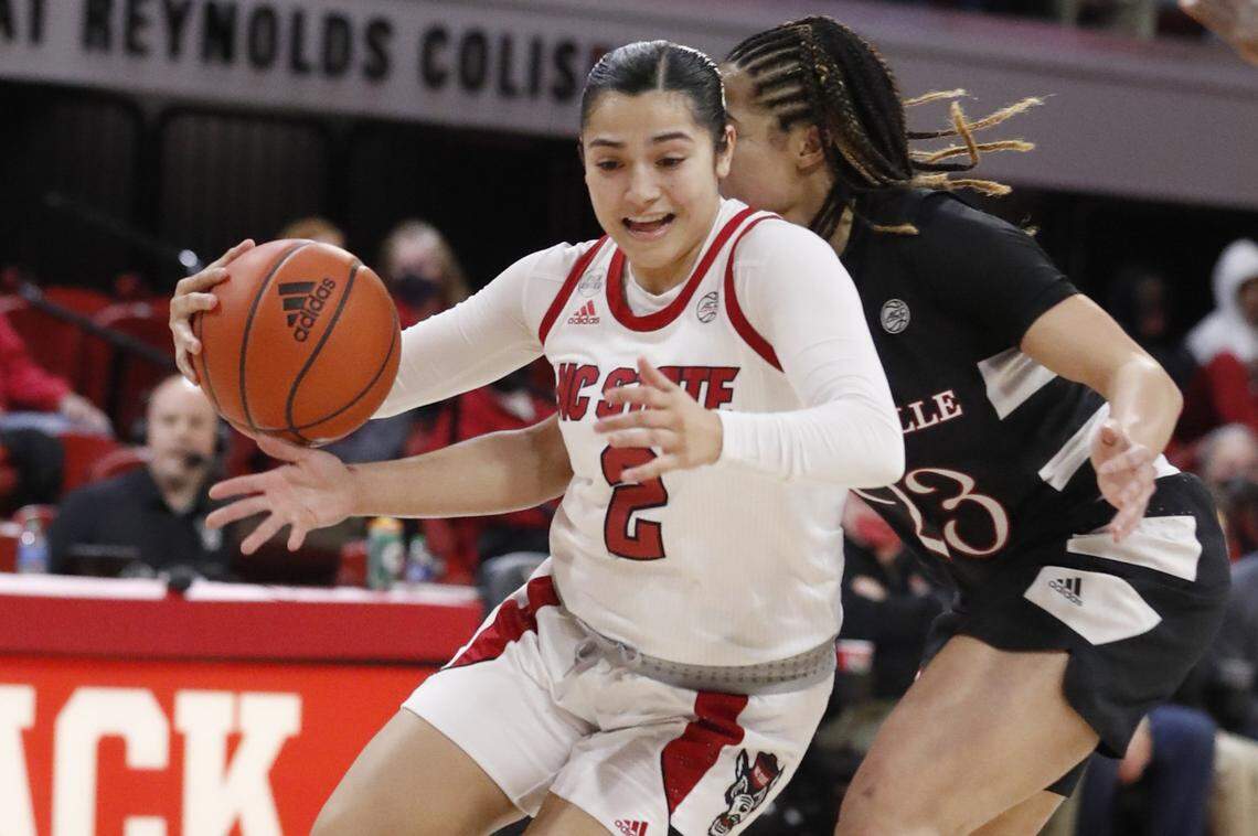N.C. State’s Raina Perez (2) drives by Louisville’s Chelsie Hall (23) during the first half of N.C. States game against Louisville at Reynolds Coliseum in Raleigh, N.C., Thursday, Jan. 20, 2022.