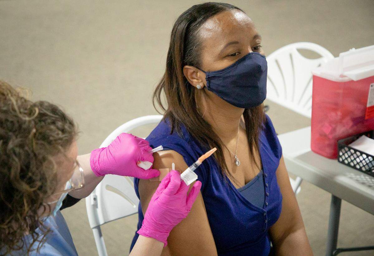 Antionette Kenan, right, a sixth grade science teacher at Holly Ridge Middle School, receives her first dose of the Moderna COVID-19 vaccine from the UNC Health mobile vaccine clinic at Praise Temple Apostolic Faith Church, on Wednesday, Feb. 24, 2021, in Clayton, N.C.