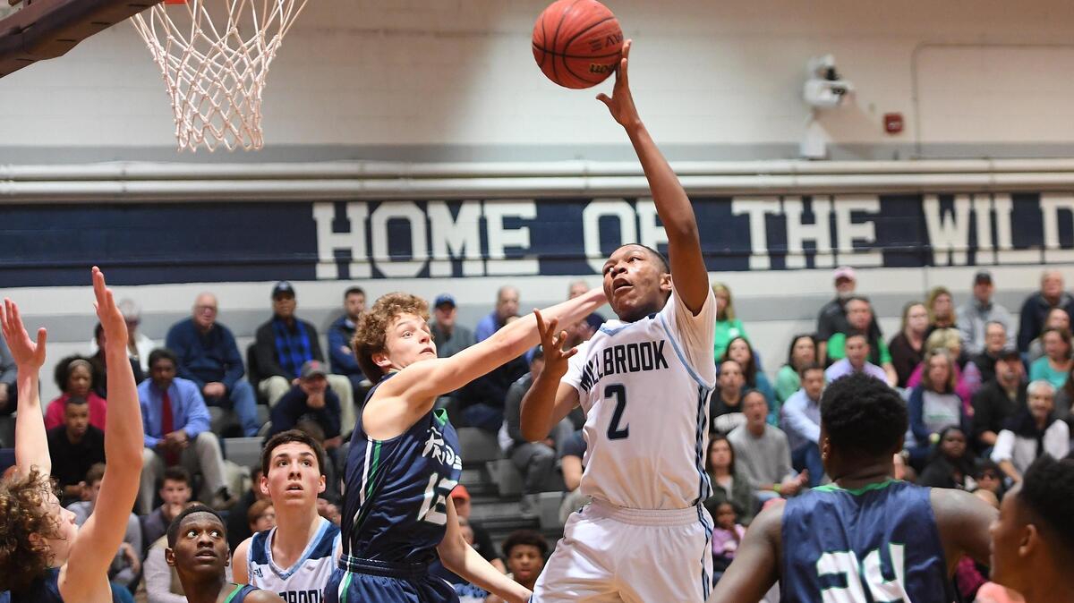 Jalen McCoy (2) of Millbrook scores a basket against Scott Martin (12) and RJ Wilson (24) of Leesville Road. The Leesville Road Pride visited the Millbrook Wildcats in a high school men basketball game on March 28, 2019.