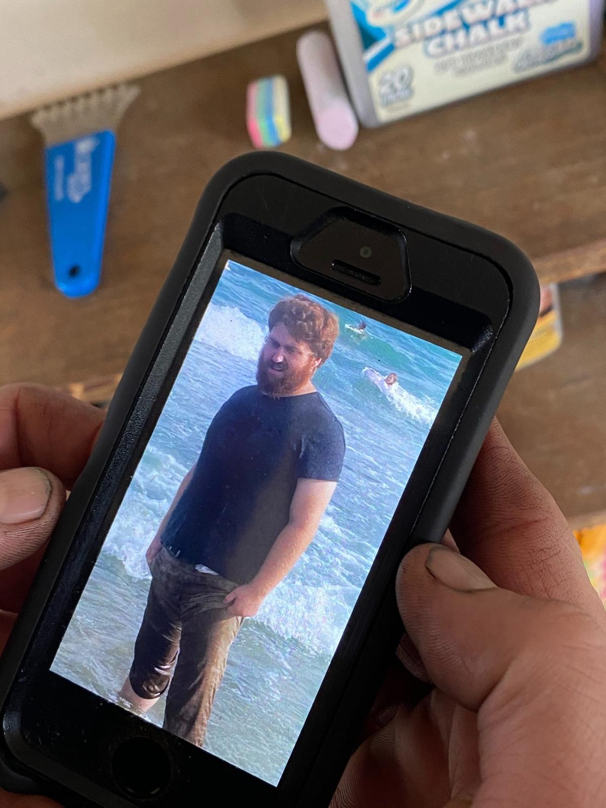 Dylan Wall, 23, wanted to build a family with his wife and 5-year-old son. His father, Phillip, shows a photo on his phone the day after he was shot on his UPS route.