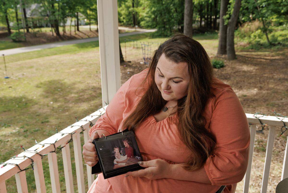 Nicole Holliday, photographed at her home in Wake Forest on Friday, April 17, 2026, holds a photograph of her as a young child with her mother, Victoria Benhoff. Benhoff died in March 2025 after ingesting fentanyl. 