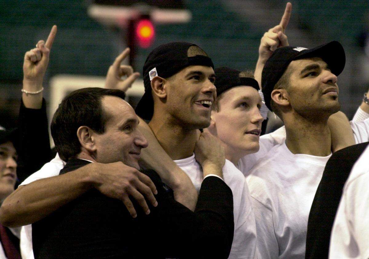 Duke coach Mike Krzyzewski hugs Shane Battier as Mike Dunleavy, and Carlos Boozer watch a video following the trophy presentation after the Blue Devils 82-72 NCAA championship win over Arizona in 2001.