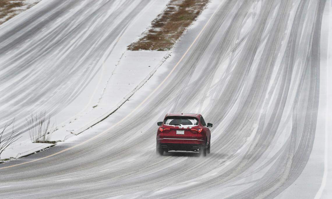 A car travels up an icy slope of U.S. 70 near Brier Creek in Raleigh, N.C. Sunday morning, January 16, 2022 as a mixture of sleet and freezing rain falls on the Triangle area.