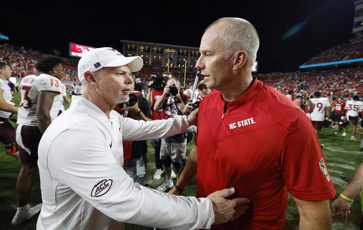 Virginia Tech interim head coach Philip Montgomery talks to N.C. State head coach Dave Doeren after Virginia Tech’s 23-21 victory over N.C. State at Carter-Finley Stadium in Raleigh, N.C., Saturday, Sept. 27, 2025.
