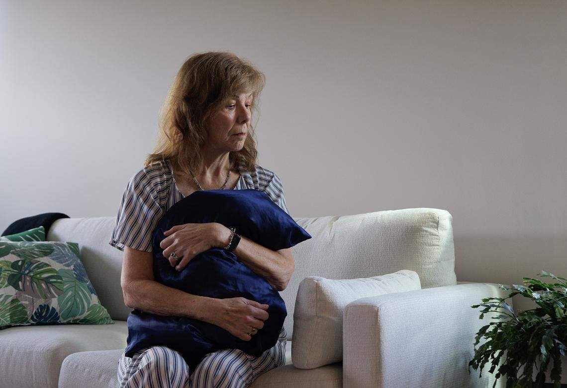 Jill Rohner holds a pillow that belonged to her partner, John, as she sits in her new home on Tuesday, Oct. 7, 2025. John was fatally shot by her ex-husband, against whom she had a domestic violence protective order, in late January.