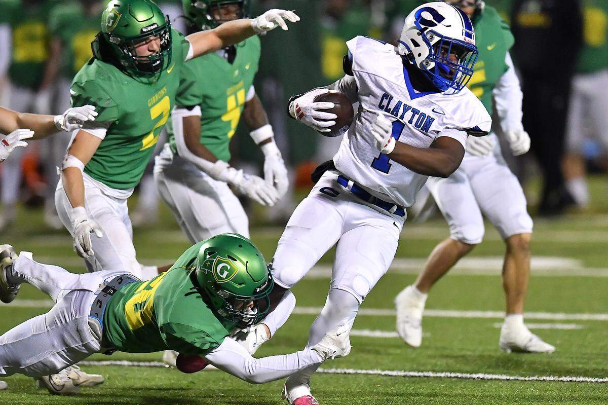 Cardinal Gibbons defensive back Jack Richards (20) grapples Clayton running back Noah Smith (1) during the second half. The Clayton Comets and the Cardinal Gibbons Crusaders met in the East Regional Final of the NCHSAA 7A Football Championship in Clayton, N.C. on December 4, 2025.