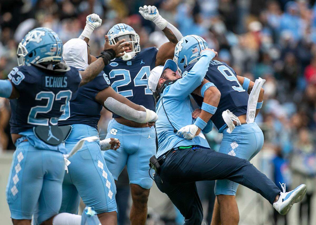 North Carolina defensive graduate assistant Taylor Anderson embraces Cam’Ron Kelly (9) after his interception in the fourth quarter against Wake Forest on Saturday, November 6, 2021 at Kenan Stadium in Chapel Hill, N.C