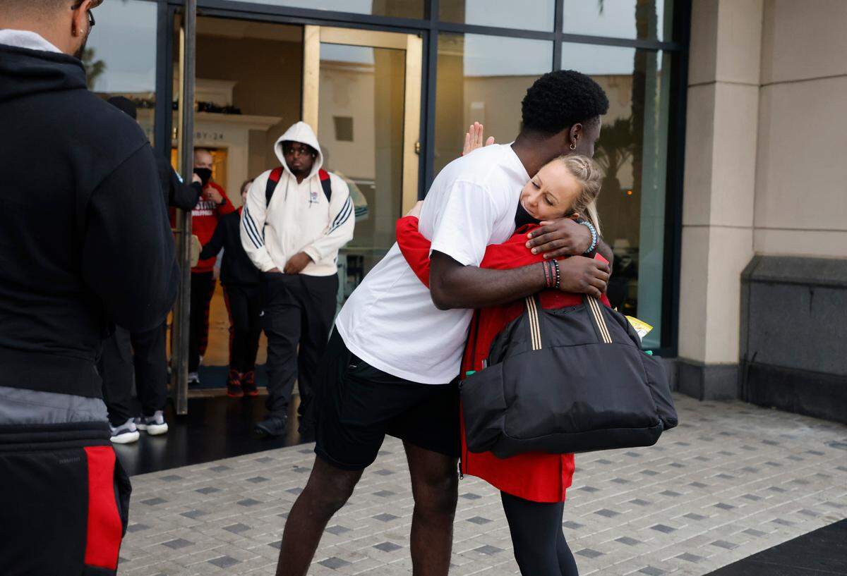 N.C. State wide receiver Emeka Emezie hugs associate athletic trainer Alyse King as the N.C. State players and staff depart the team hotel to head to the airport in San Diego, CA Wednesday, Dec. 29, 2021.