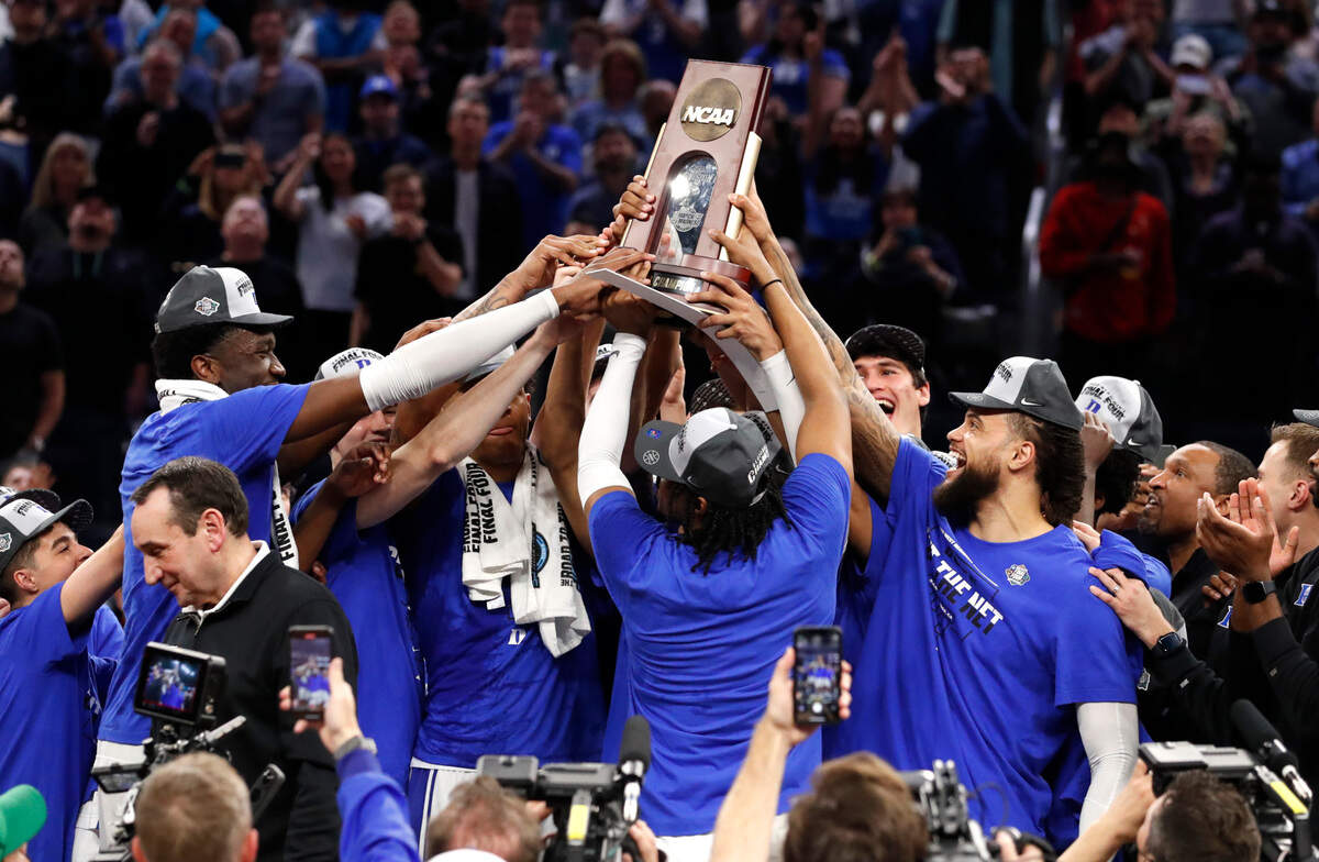 The team holds up the championship trophy after Duke’s 78-69 victory over Arkansas in the NCAA Tournament West Regional finals at the Chase Center in San Francisco, Calif., Saturday, March 26, 2022.