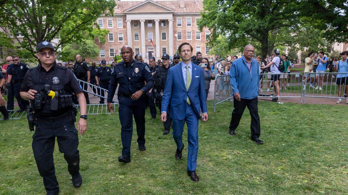 Interim Chancellor Lee Roberts and police prepare to rehang an American flag after it was brought down by demonstrators and replaced with a Palestinian flag Tuesday, April 30, 2024 during protests at UNC-Chapel Hill..