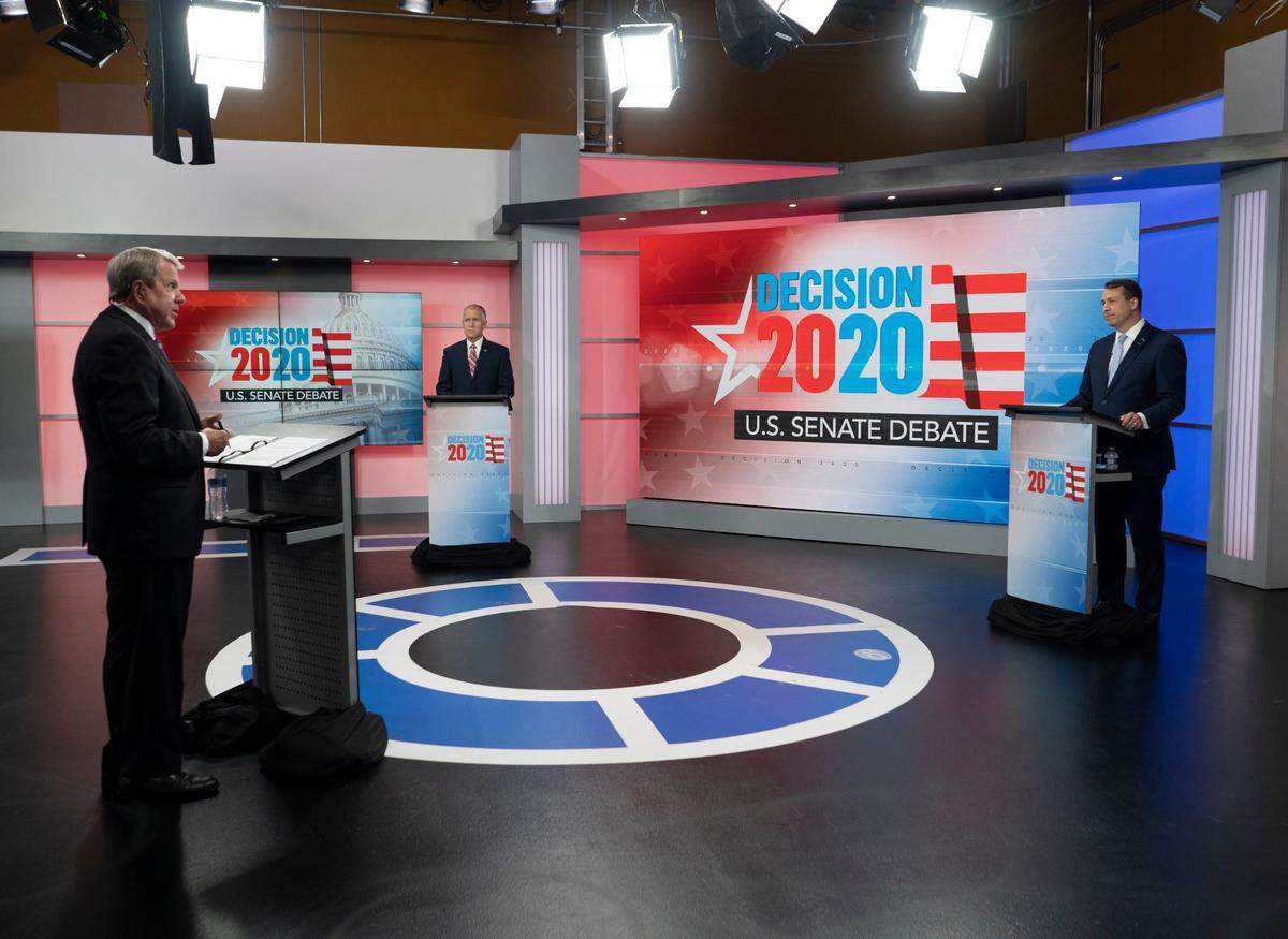 U.S. Sen. Thom Tillis, R-N.C., back left, and Democratic challenger Cal Cunningham, right, participate in a televised debate, moderated by WRAL anchor David Crabtree, front left, Monday, Sept. 14, 2020, at the WRAL-TV studios in Raleigh, N.C.