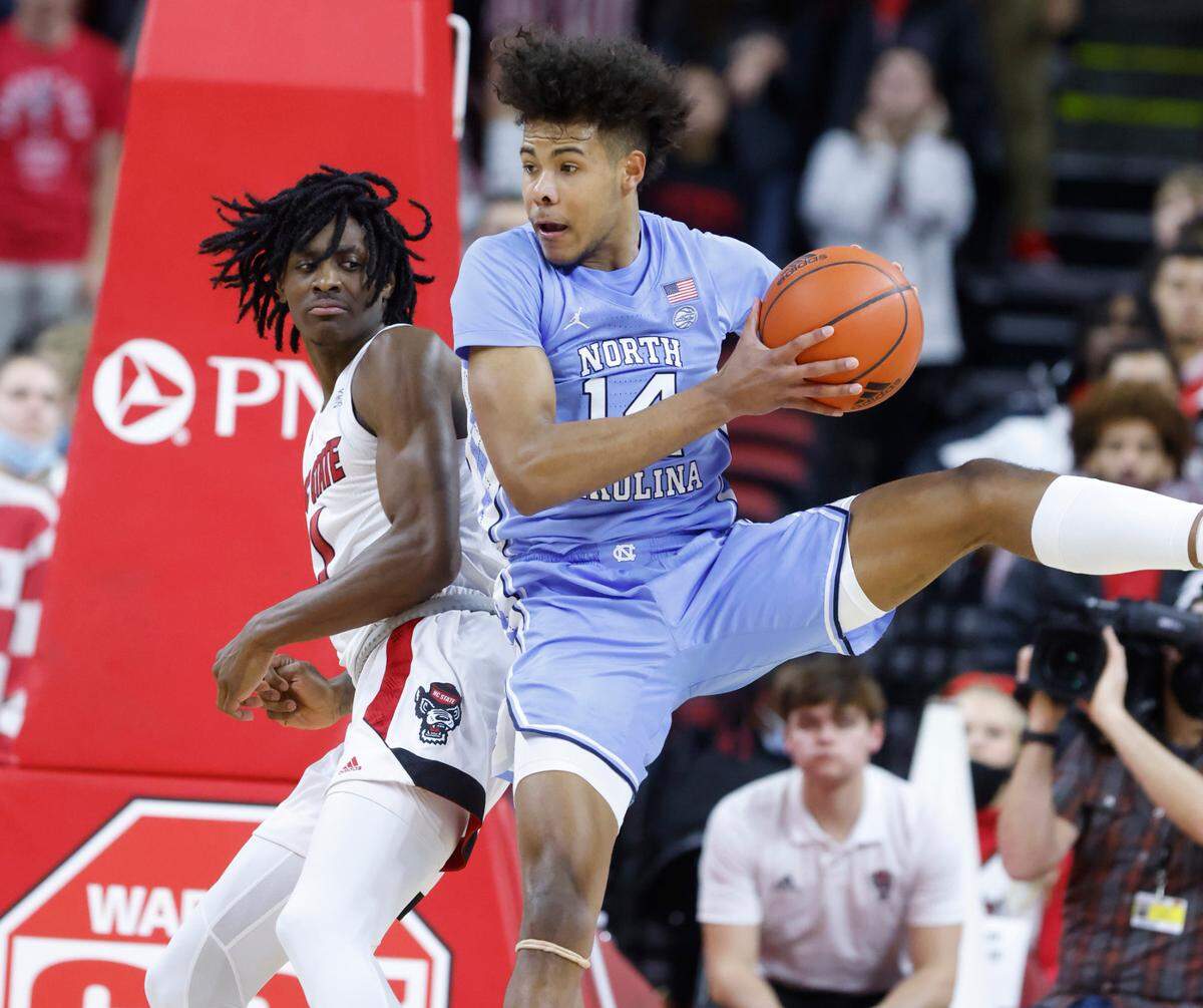 North Carolina’s Puff Johnson (14) pulls in the rebound from N.C. State’s Dereon Seabron (1) during the second half of UNC’s 84-74 victory over N.C. State at PNC Arena in Raleigh, N.C., Saturday, Feb. 26, 2022.