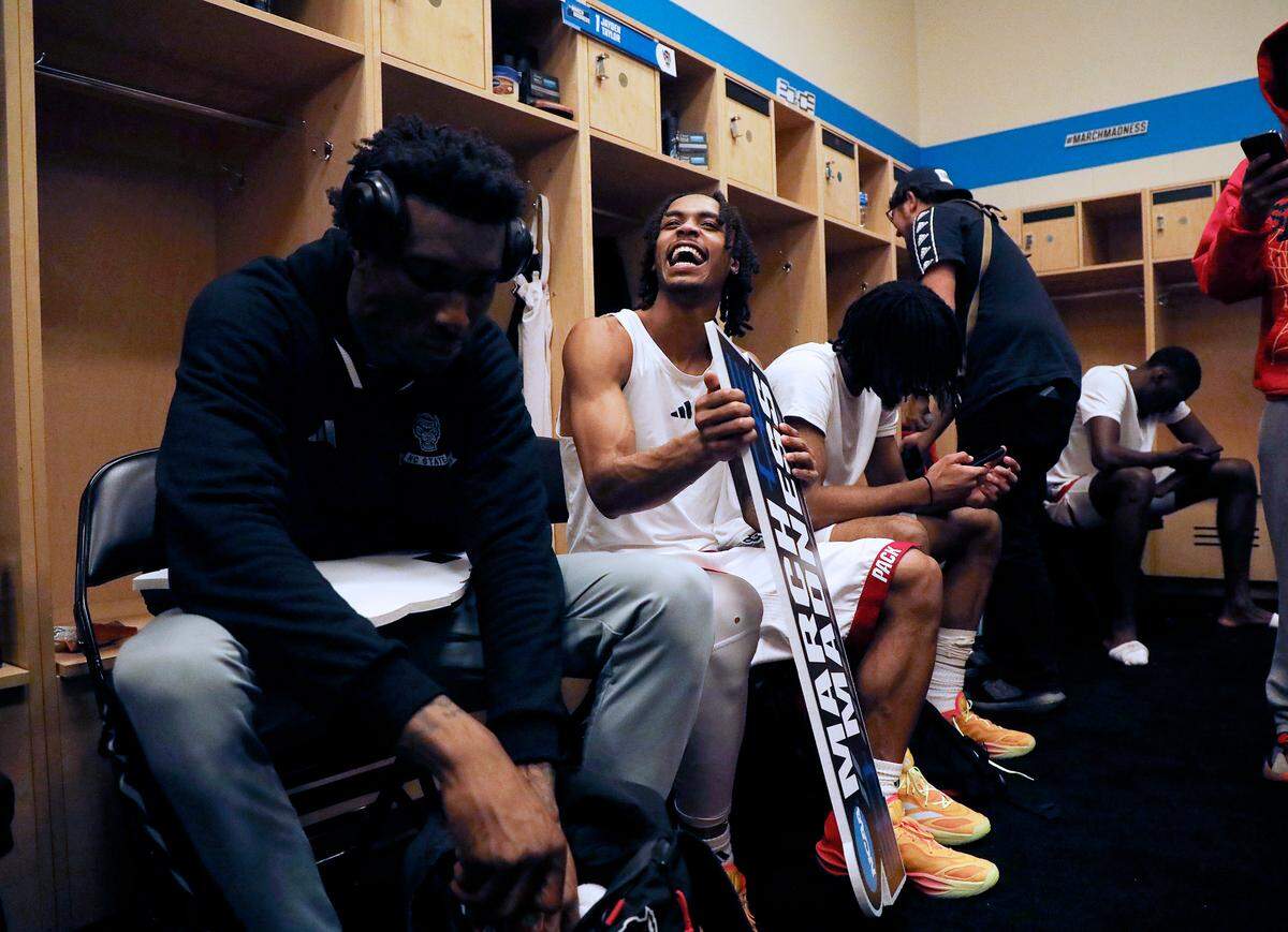 N.C. State’s Breon Pass, center, smiles while holding a March Madness sign in the locker room following the Wolfpack’s 79-73 overtime win against Oakland in the second round of the NCAA Tournament on Saturday, March 23, 2024, at PPG Paints Arena in Pittsburgh, Pa.