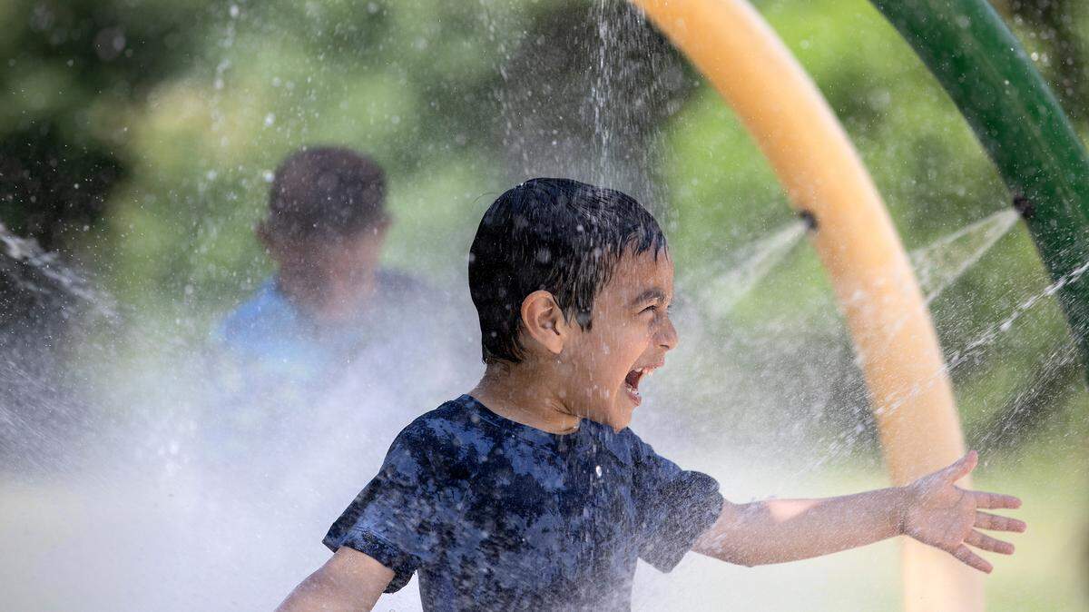 Liam Rodriguez laughs while running through a sprayground at Forest Hills Park on Monday, July 3, 2023, in Durham, N.C.