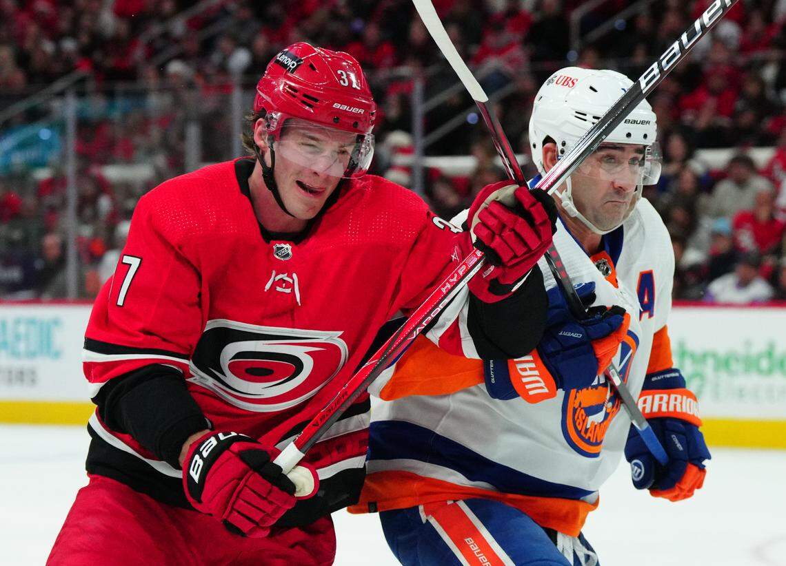 Dec 23, 2023; Raleigh, North Carolina, USA; Carolina Hurricanes right wing Andrei Svechnikov (37) and New York Islanders right wing Cal Clutterbuck (15) battle for position during the first period at PNC Arena. Mandatory Credit: James Guillory-USA TODAY Sports
