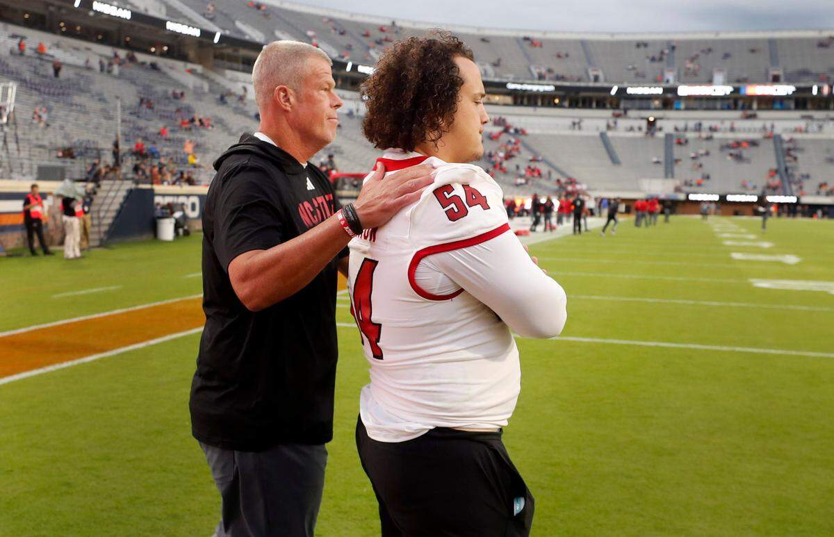 N.C. State offensive line coach Garett Tujague talks with Dylan McMahon (54) during warmups before the Wolfpack’s game against Virginia at Scott Stadium in Charlottesville, Va., Friday, Sept. 22, 2023.